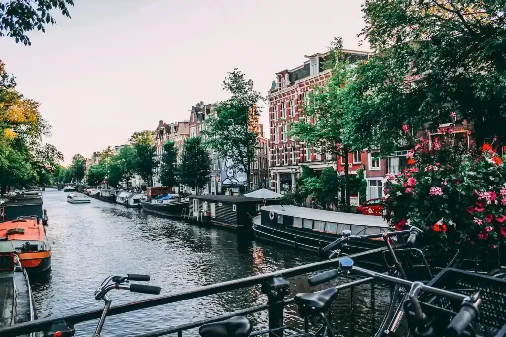 A scenic view of Amsterdam's iconic canals lined with historic buildings and boats under a clear blue sky.