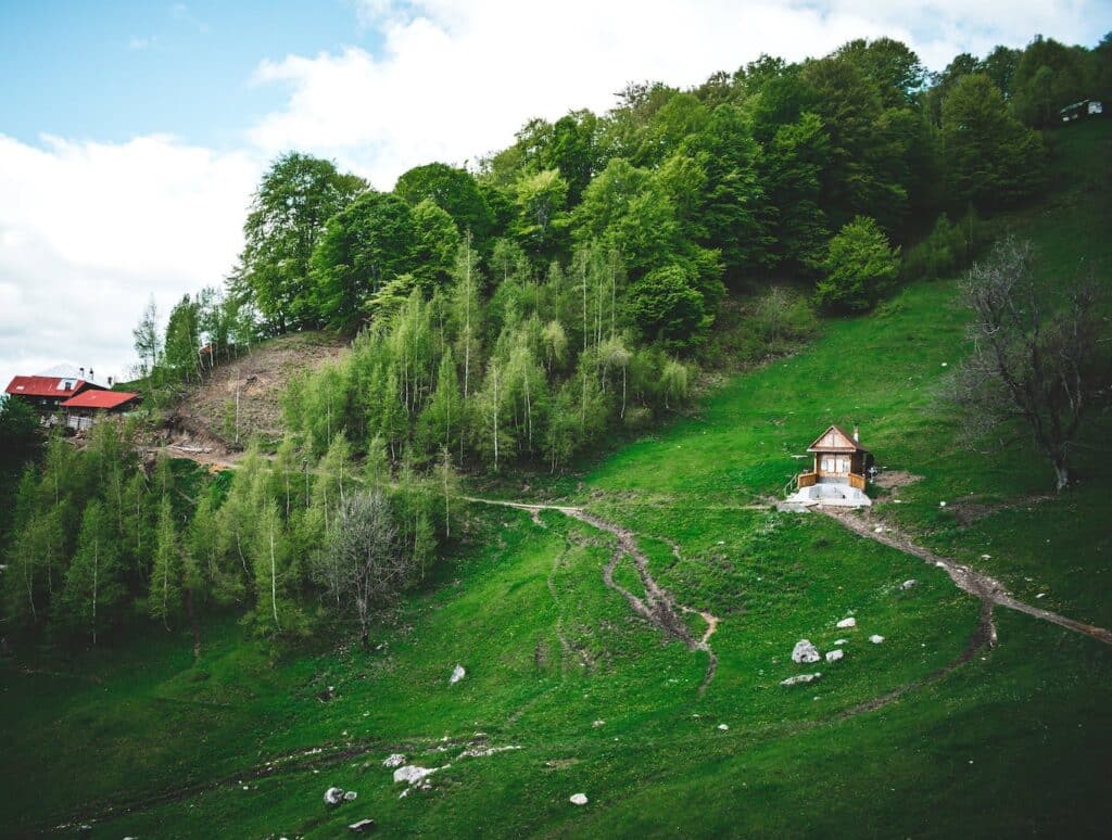 A small church sits on a hillside surrounded by trees, showcasing a serene rural landscape.
