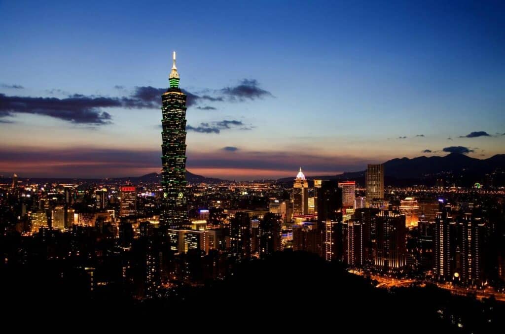 Taipei Tower illuminated at night, showcasing vibrant colors against a dark sky.