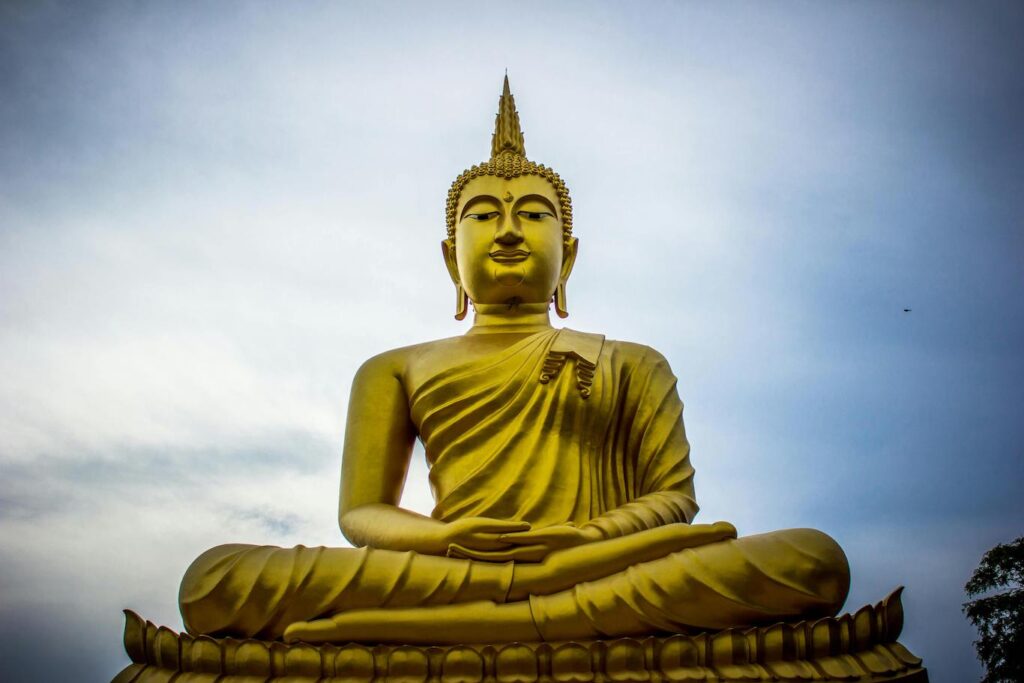 A large golden Buddha statue sits majestically atop a hill, overlooking the surrounding landscape.
