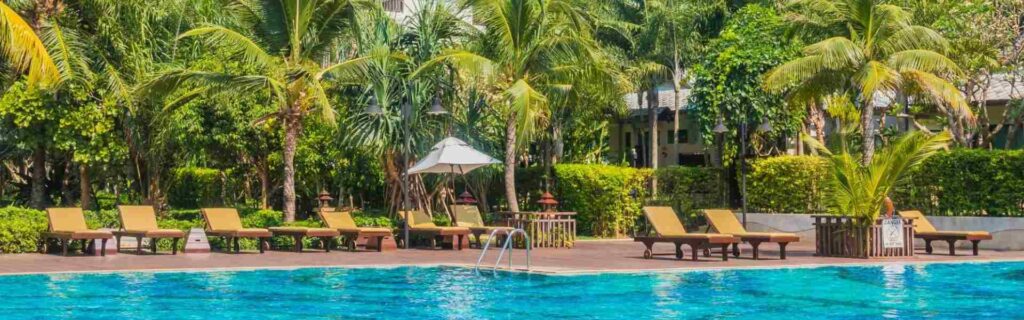 large swimming pool with palm trees and deck chairs in the background
