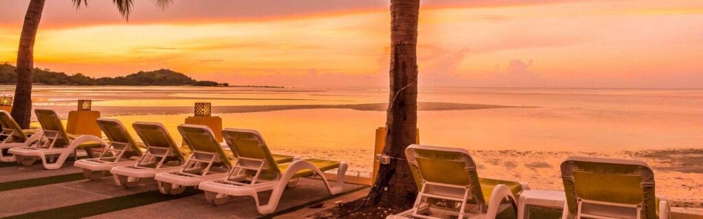 dusk with deck chairs on a beach overlooking the ocean and sunset