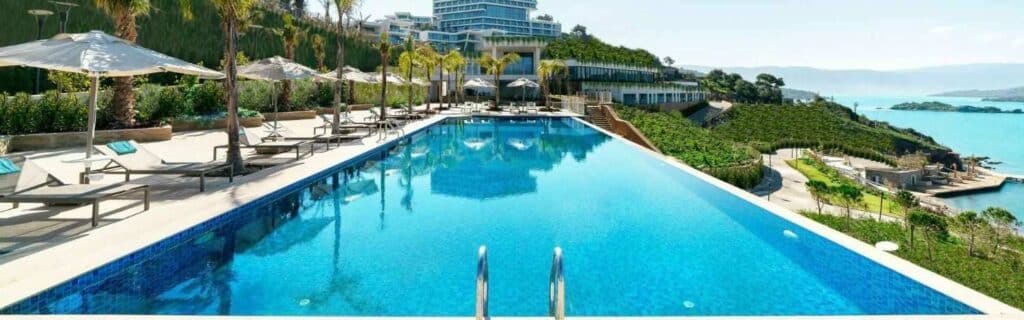 long pool and deck chairs at a resort with other hotels in the distance