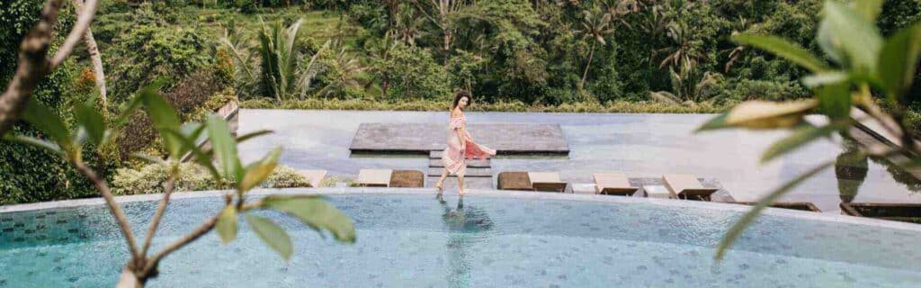 hotel guest walking across luxury swimming pool inside the costa rican rainforest.