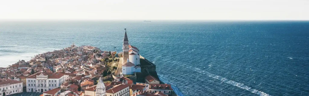 Seaside town with church, next to the Adriatic sea, in Slovenia - happiest countries in the world