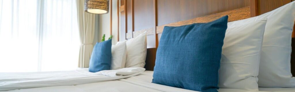a bed with blue and white pillows inside menen hotel in nauru