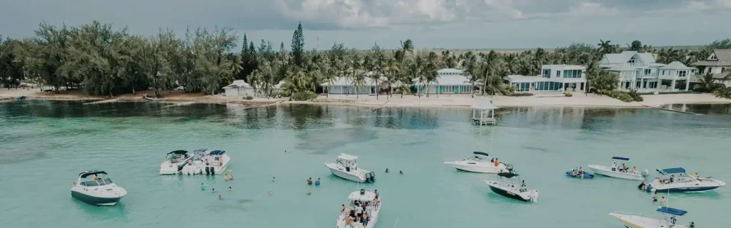 people in yachts close to the shore and beachfront property in the cayman islands