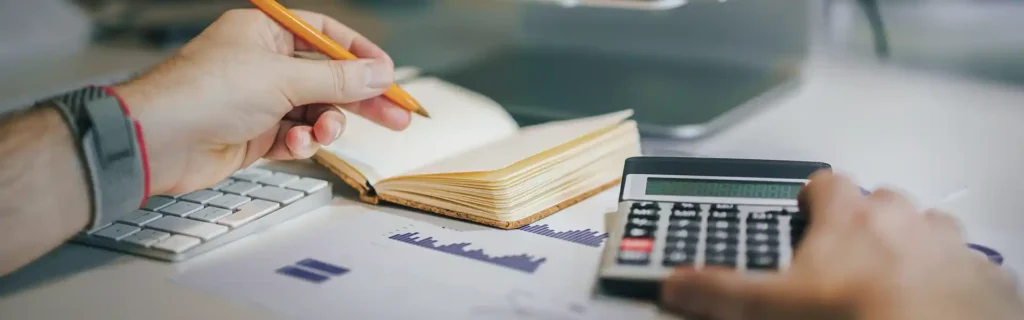 Calculator, notebook, and keyboard, with person writing down taxes in Latvia 