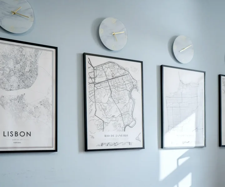 Three framed maps hang on a wall beside a round clock, creating a visually interesting and informative display.